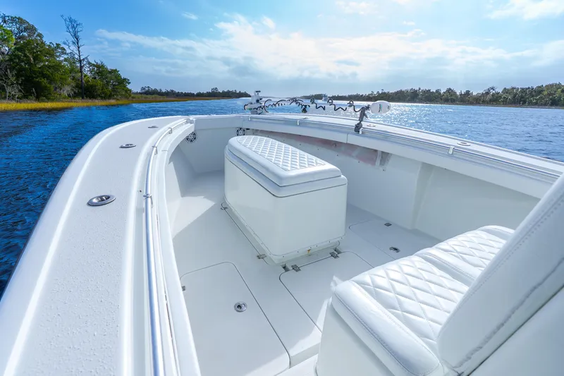 Slide: The Image of 2014 Yellowfin 32 Offshore boat interior with white seating on a calm waterway. - 13