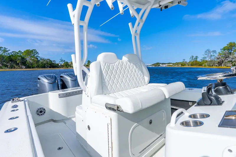 Slide: The Image of 2014 Yellowfin 32 Offshore boat interior with white seating, dual engines, and scenic water view. - 29