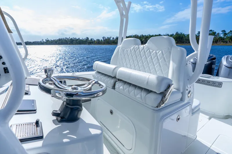 Slide: The Image of 2014 Yellowfin 32 Offshore boat interior with steering wheel and cushioned seating, on a sunny day. - 30