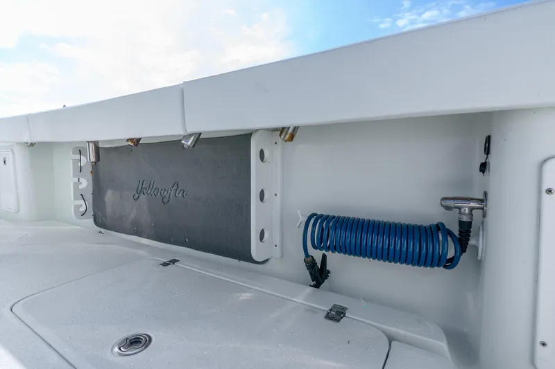 Slide: The Image of 2014 Yellowfin 32 Offshore boat deck with coiled blue hose and storage compartments. - 39