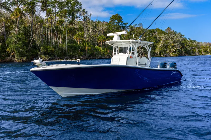 Slide: The Image of 2014 Yellowfin 32 Offshore boat on a scenic waterway with lush greenery. - 6