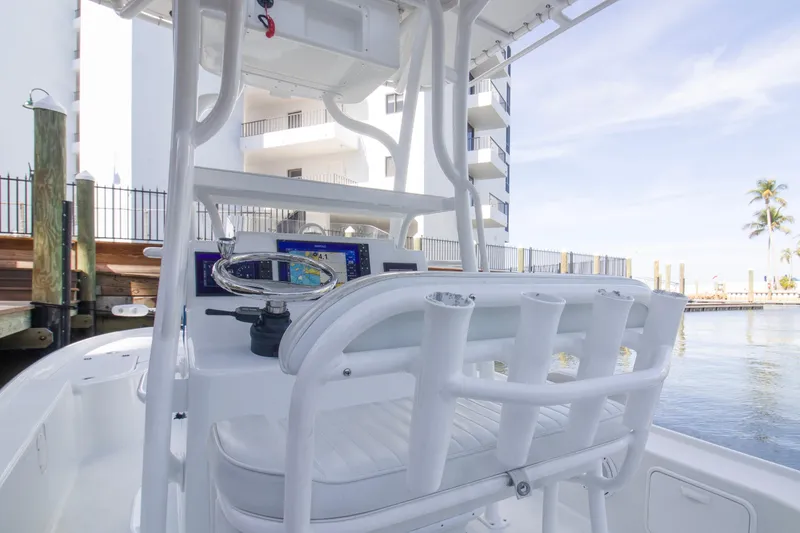 Slide: The Image of 2014 Yellowfin 24 Bay boat interior with steering wheel and control panel, docked by waterfront. - 7