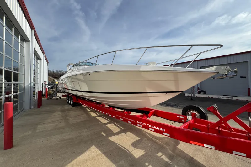Slide: The Image of 2003 Riviera Cruiser M470 Excalibur boat on red trailer outside a garage. - 3