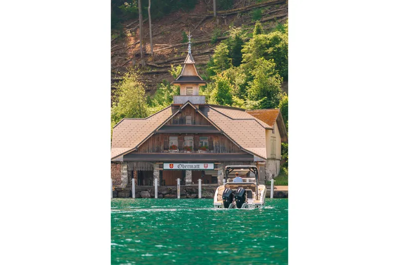 Slide: The Image of Boat on lake near rustic building, surrounded by lush greenery. - 35