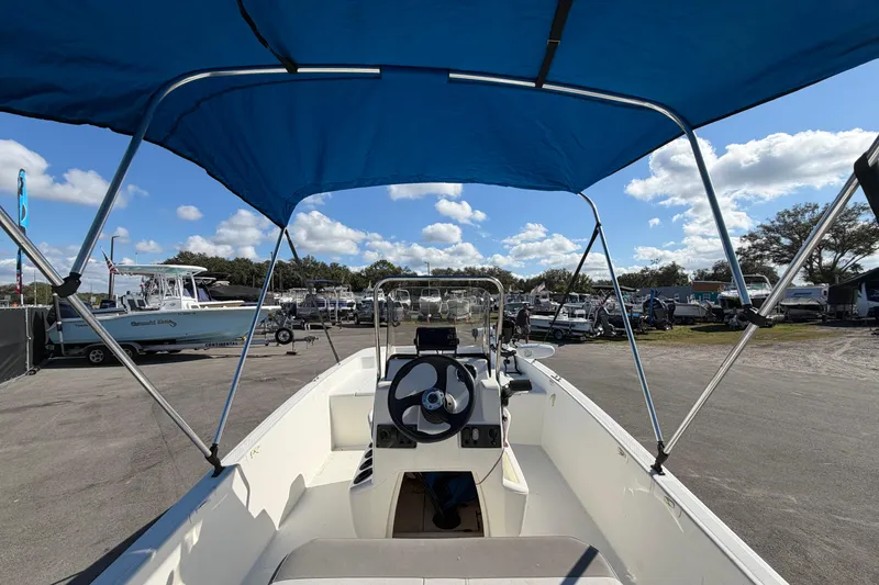 Slide: The Image of 2019 Mako Pro Skiff 15 CC boat with blue canopy on trailer, sunny day. - 10