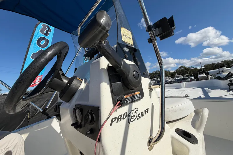 Slide: The Image of 2019 Mako Pro Skiff 15 CC boat with blue canopy in a parking lot. - 16