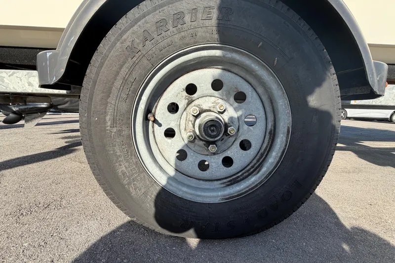 Slide: The Image of Trailer wheel of a 2019 Mako Pro Skiff 15 CC boat on asphalt. - 44