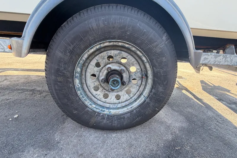 Slide: The Image of Trailer wheel of a 2019 Mako Pro Skiff 15 CC boat on pavement. - 45