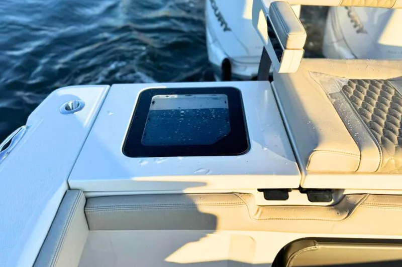 Slide: The Image of Open hatch on 2023 Solace 32 CS boat, revealing storage compartment by the water. - 19