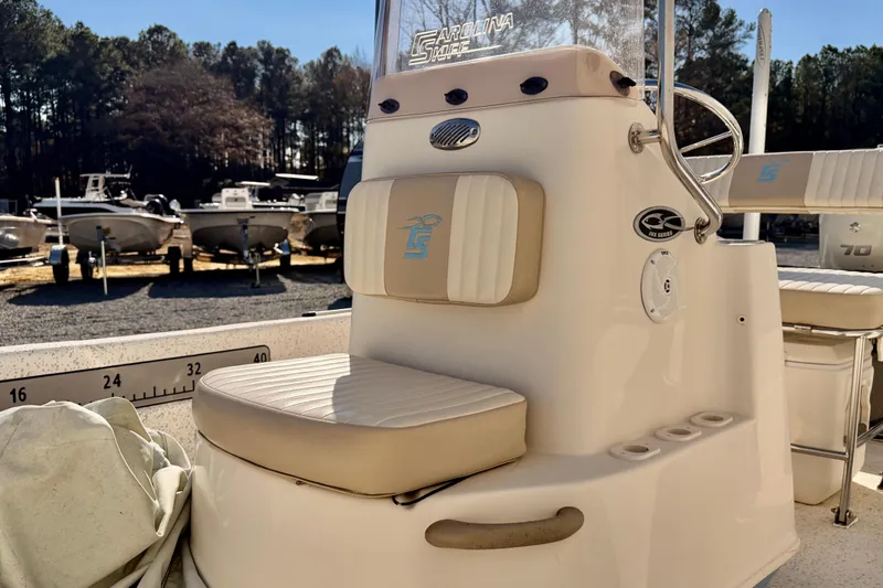 Slide: The Image of 2018 Carolina Skiff 18 JVX CC boat interior with seating and console, parked outdoors. - 4