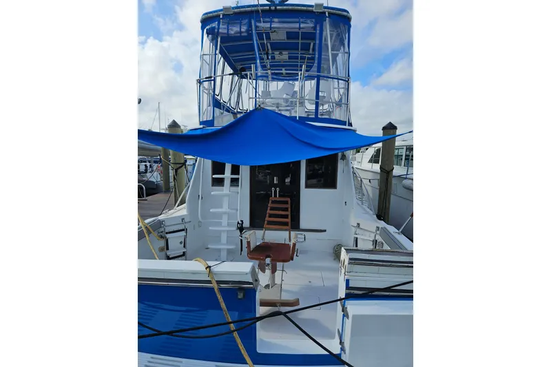 Slide: The Image of 1988 Symbol 44' Sportfish boat with blue canopy docked at marina. - 1