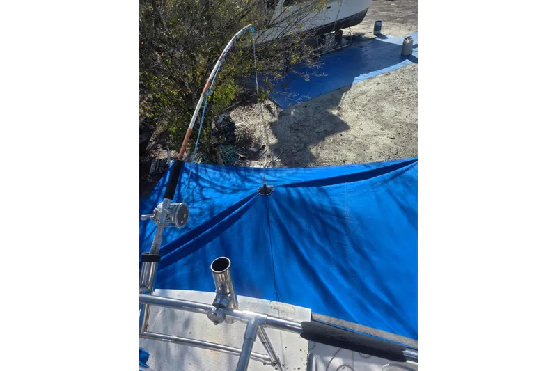 Slide: The Image of 1988 Symbol 44' Sportfish boat with blue tarp and fishing rod setup. - 13