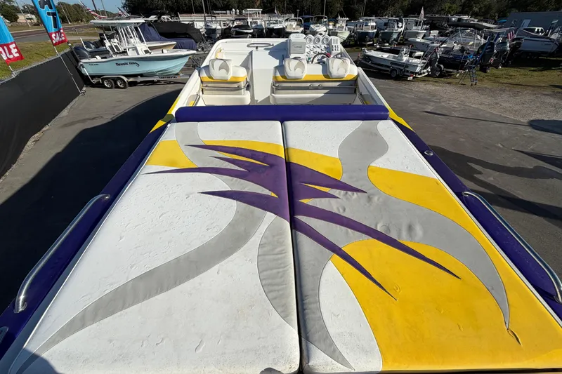 Slide: The Image of 1999 Black Thunder XT-430 boat with vibrant yellow and purple design, docked among other boats. - 11