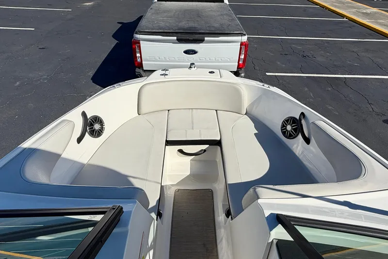 Slide: The Image of 2023 Sea Ray SPX 210 Outboard boat interior with seating and speakers, parked near a truck. - 11