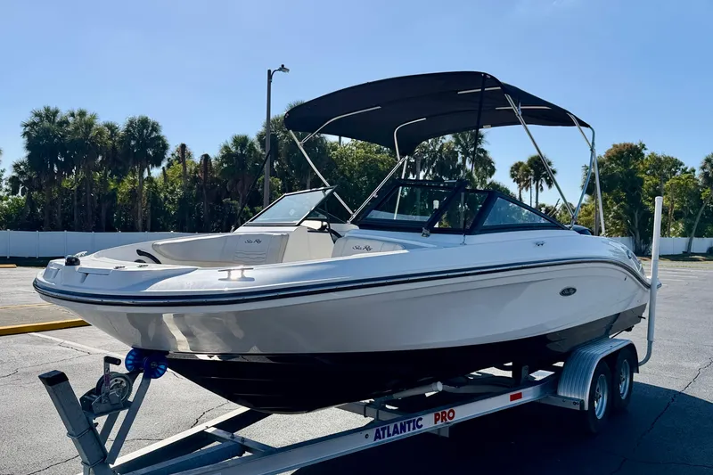 Slide: The Image of 2023 Sea Ray SPX 210 Outboard boat on trailer, parked outdoors with palm trees. - 2