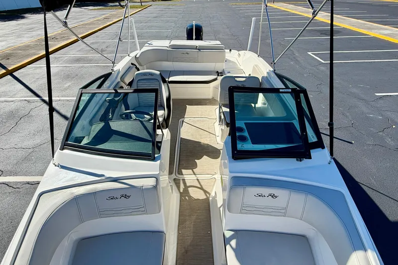 Slide: The Image of 2023 Sea Ray SPX 210 Outboard boat interior with seating and windshield in a parking lot. - 24