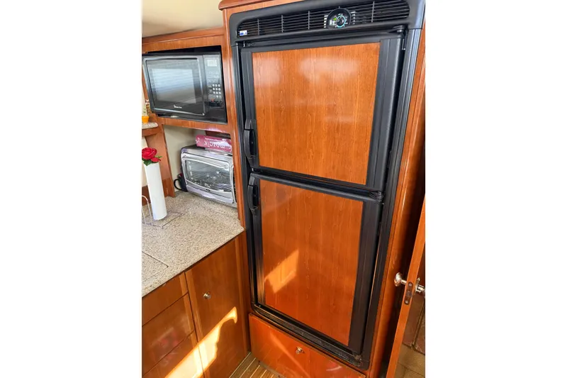 Slide: The Image of 2007 Meridian 459 Motoryacht kitchen with wood-paneled fridge, microwave, and toaster oven. - 30