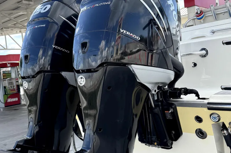 Slide: The Image of 2014 Mako 284 Center Console boat stored in a covered garage with vehicles. - 2