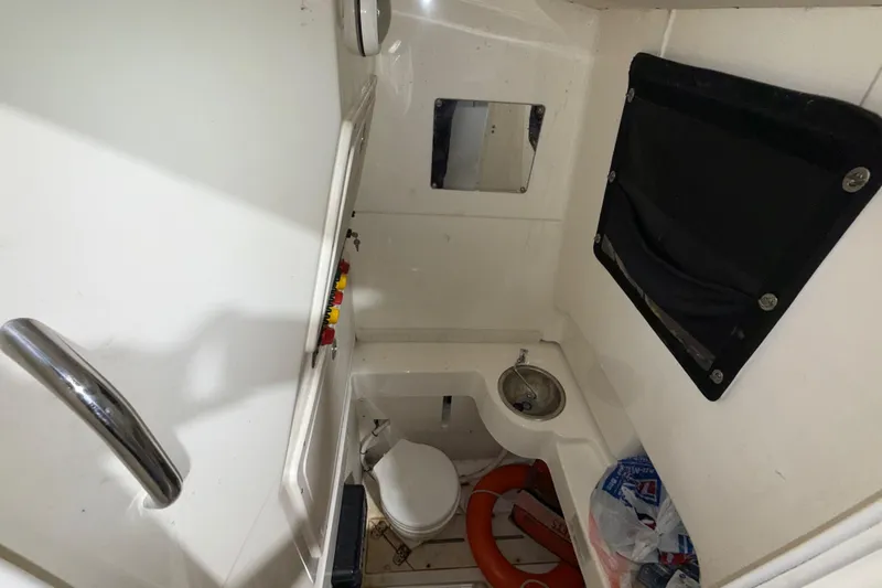 Slide: The Image of Interior of a 2014 Mako 284 Center Console boat, featuring a compact restroom area. - 24