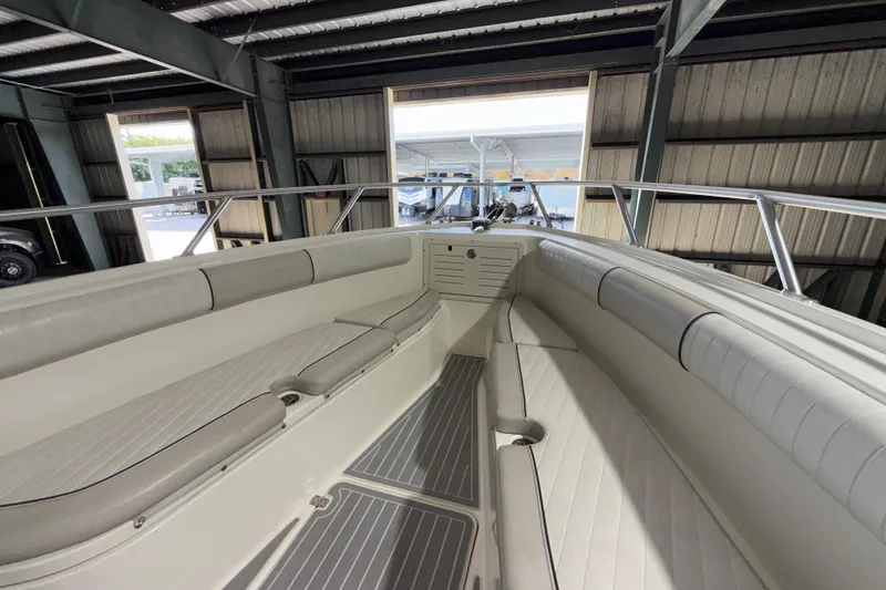 Slide: The Image of 2014 Mako 284 Center Console boat interior with cushioned seating in a covered storage area. - 34