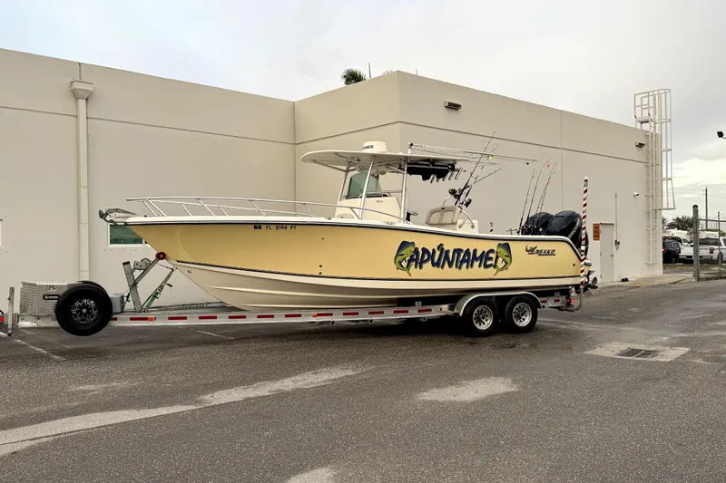 Slide: The Image of 2014 Mako 284 Center Console boat on trailer, parked near a building. - 43