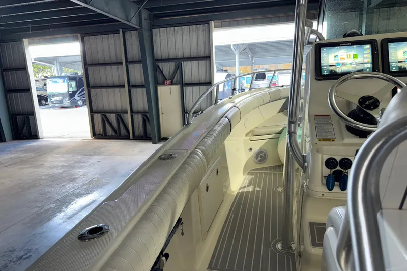 Slide: The Image of 2014 Mako 284 Center Console boat interior with dual screens and steering wheel in a garage. - 9