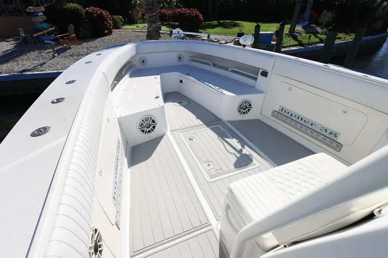 Slide: The Image of 2005 Jupiter 38 FS boat interior with white seating and deck, docked near a garden. - 21