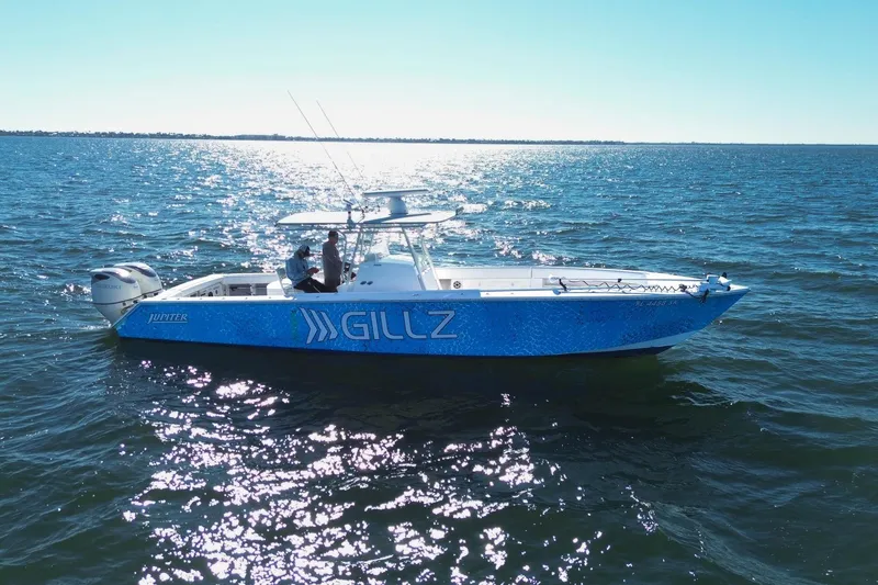 Slide: The Image of 2005 Jupiter 38 FS boat on open water, sunny day, blue hull with "Gillz" branding. - 3