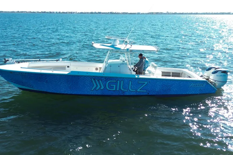 Slide: The Image of 2005 Jupiter 38 FS boat on water, blue design, Suzuki engines, person onboard. - 5