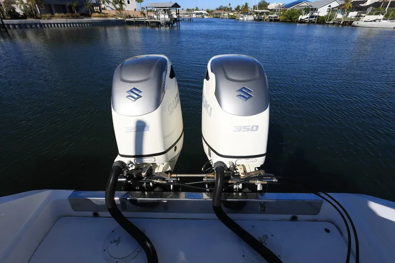 Slide: The Image of Twin Suzuki 350 outboard engines on a 2005 Jupiter 38 FS boat, docked in a serene marina. - 6