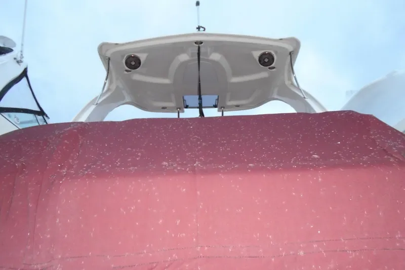 Slide: The Image of 2013 Chaparral 327 SSX boat with red and white hull, docked outdoors. - 4