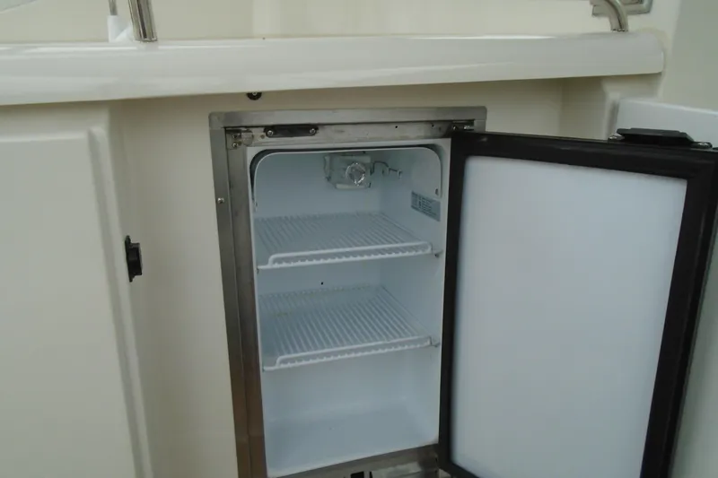 Slide: The Image of Open mini fridge on 2003 Cruisers Yachts 3470 Express boat, showing empty shelves. - 17