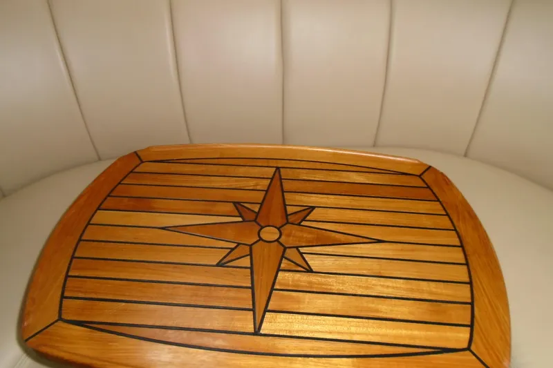 Slide: The Image of 2003 Cruisers Yachts 3470 Express interior with wooden table featuring star design. - 34