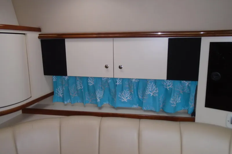 Slide: The Image of 2003 Cruisers Yachts 3470 Express interior with blue coral-patterned curtains and beige seating. - 35
