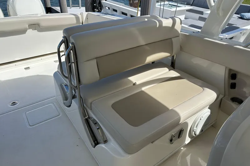 Slide: The Image of 2018 Boston Whaler 320 Vantage boat seating area with beige cushions and stainless steel accents. - 10