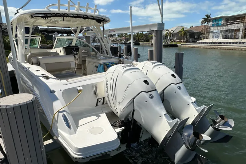 Slide: The Image of 2018 Boston Whaler 320 Vantage docked, featuring dual outboard engines, in a sunny marina setting. - 17