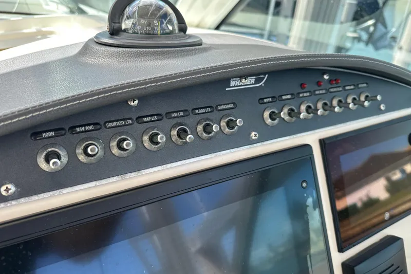 Slide: The Image of Control panel of a 2018 Boston Whaler 320 Vantage boat with various switches and compass. - 5