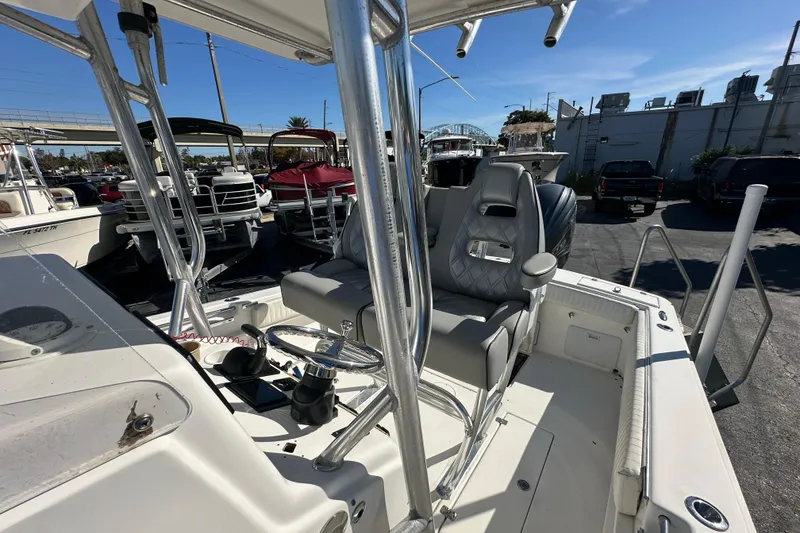 Slide: The Image of 2005 Topaz 24 Silverhawk boat interior with steering wheel and seating, docked under clear sky. - 12
