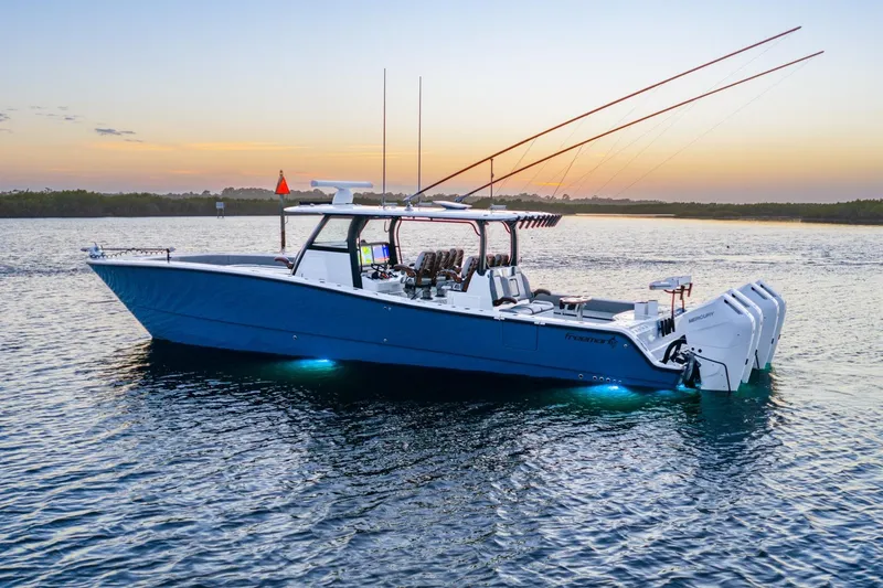 Slide: The Image of 2025 Freeman 43 boat on water at sunset, featuring blue hull and twin engines. - 2