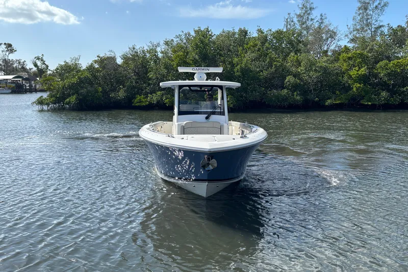 Slide: The Image of 2023 Pursuit S 328 Sport boat navigating a calm waterway with lush greenery. - 2