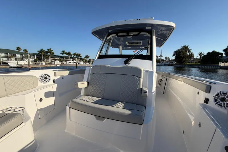 Slide: The Image of 2023 Pursuit S 328 Sport boat interior with seating, on a sunny waterfront. - 20