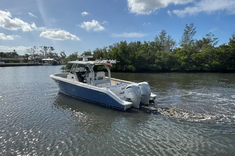 Slide: The Image of 2023 Pursuit S 328 Sport boat cruising on a calm river under a clear blue sky. - 5