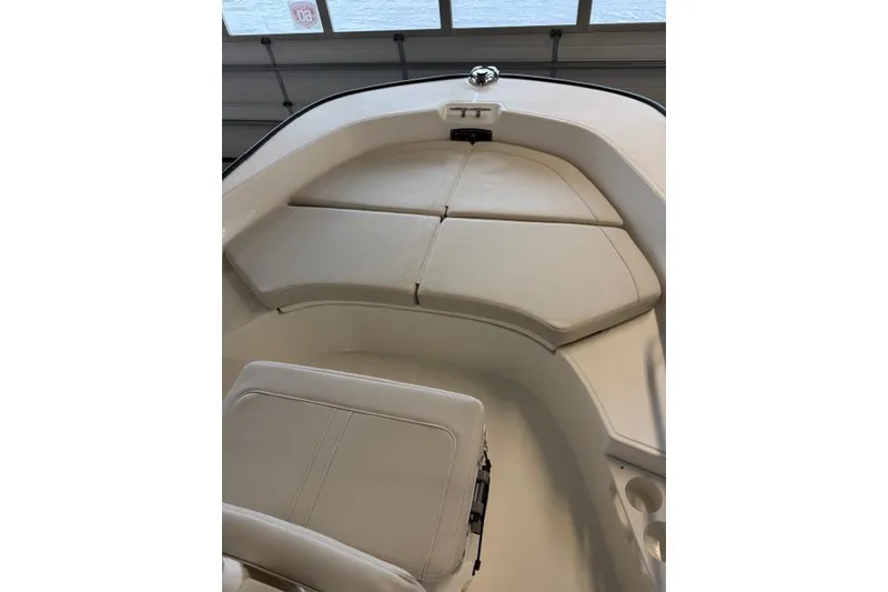 Slide: The Image of 2026 Boston Whaler 170 Montauk boat interior with cushioned seating in a garage setting. - 13