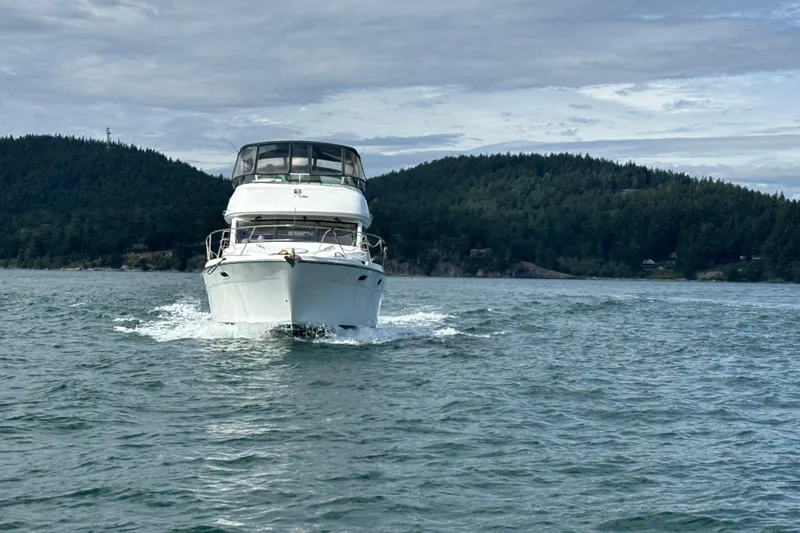 Slide: The Image of 2000 Bayliner 3788 Command Bridge Motoryacht cruising on a scenic lake with forested hills. - 5