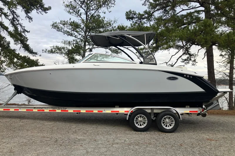 The Image of 2021 Cobalt R7 Surf boat on trailer, parked near trees and lake. - 1