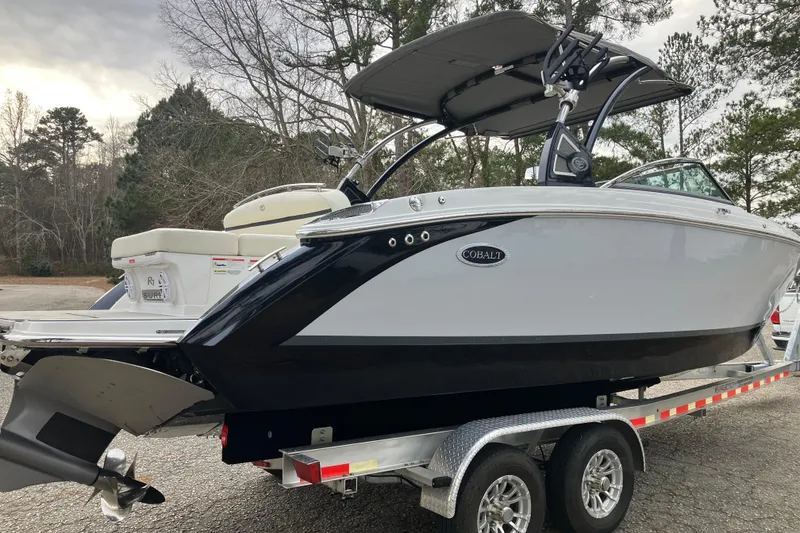 Slide: The Image of 2021 Cobalt R7 Surf boat on trailer, parked outdoors with trees in background. - 6