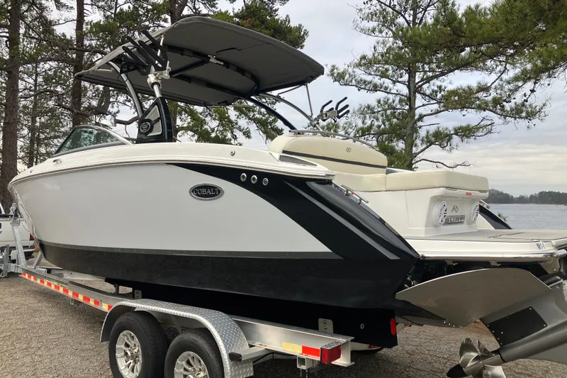 Slide: The Image of 2021 Cobalt R7 Surf boat on trailer, parked near a lake with trees. - 8