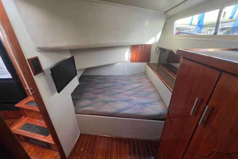 Slide: The Image of 1989 Bayliner 3888 Motoryacht cabin with bed, TV, and wooden cabinetry. - 11