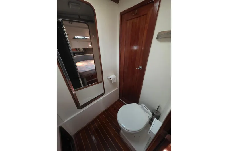 Slide: The Image of 1989 Bayliner 3888 Motoryacht bathroom with wooden door, mirror, and toilet. - 28