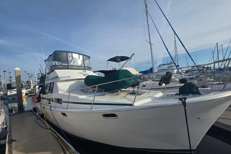 Slide: The Image of 1989 Bayliner 3888 Motoryacht docked at marina under clear sky. - 3